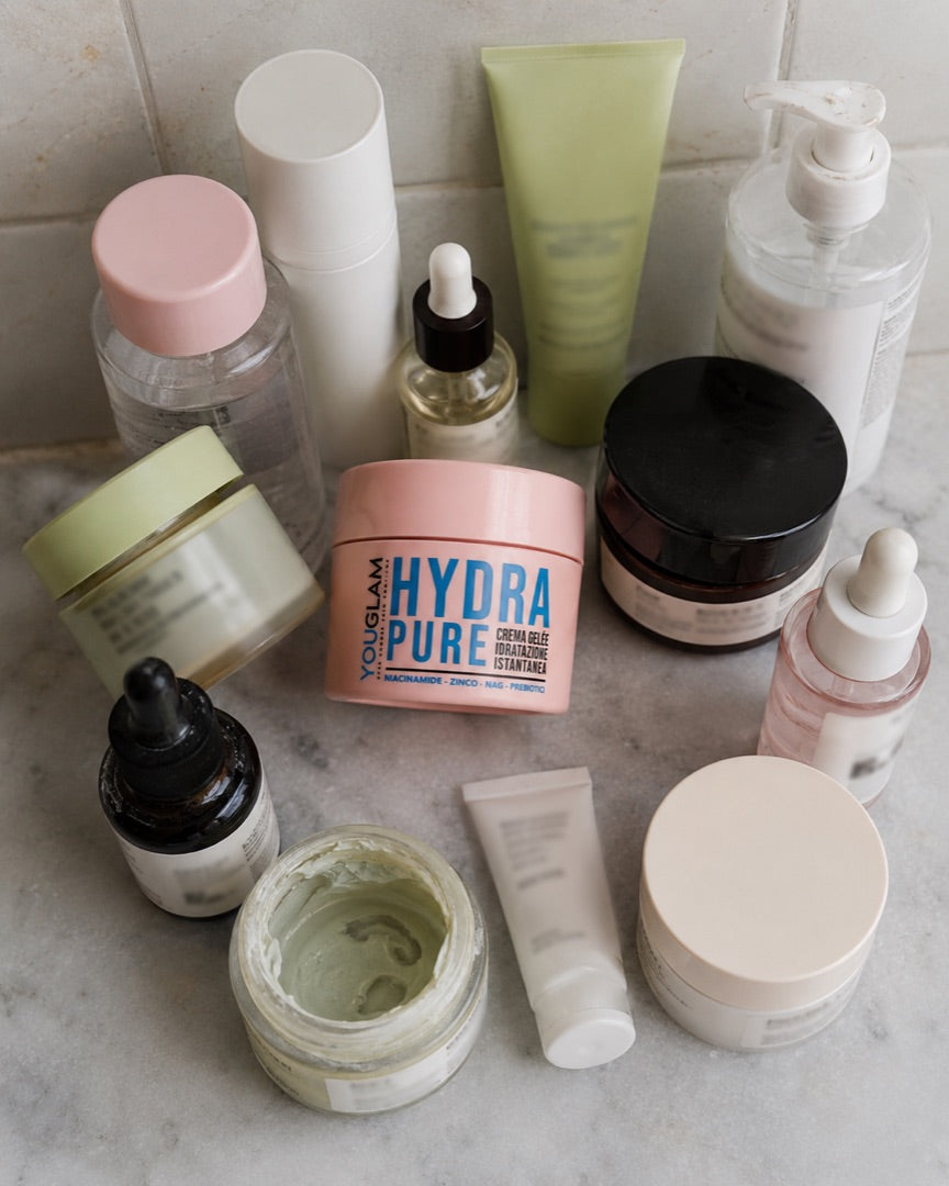 Molti barattoli di creme diverse allineati sul ripiano di un bagno
